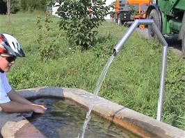 Gavin makes use of a very welcome water fountain at a farm near Penthalaz, 44.4 miles into the ride